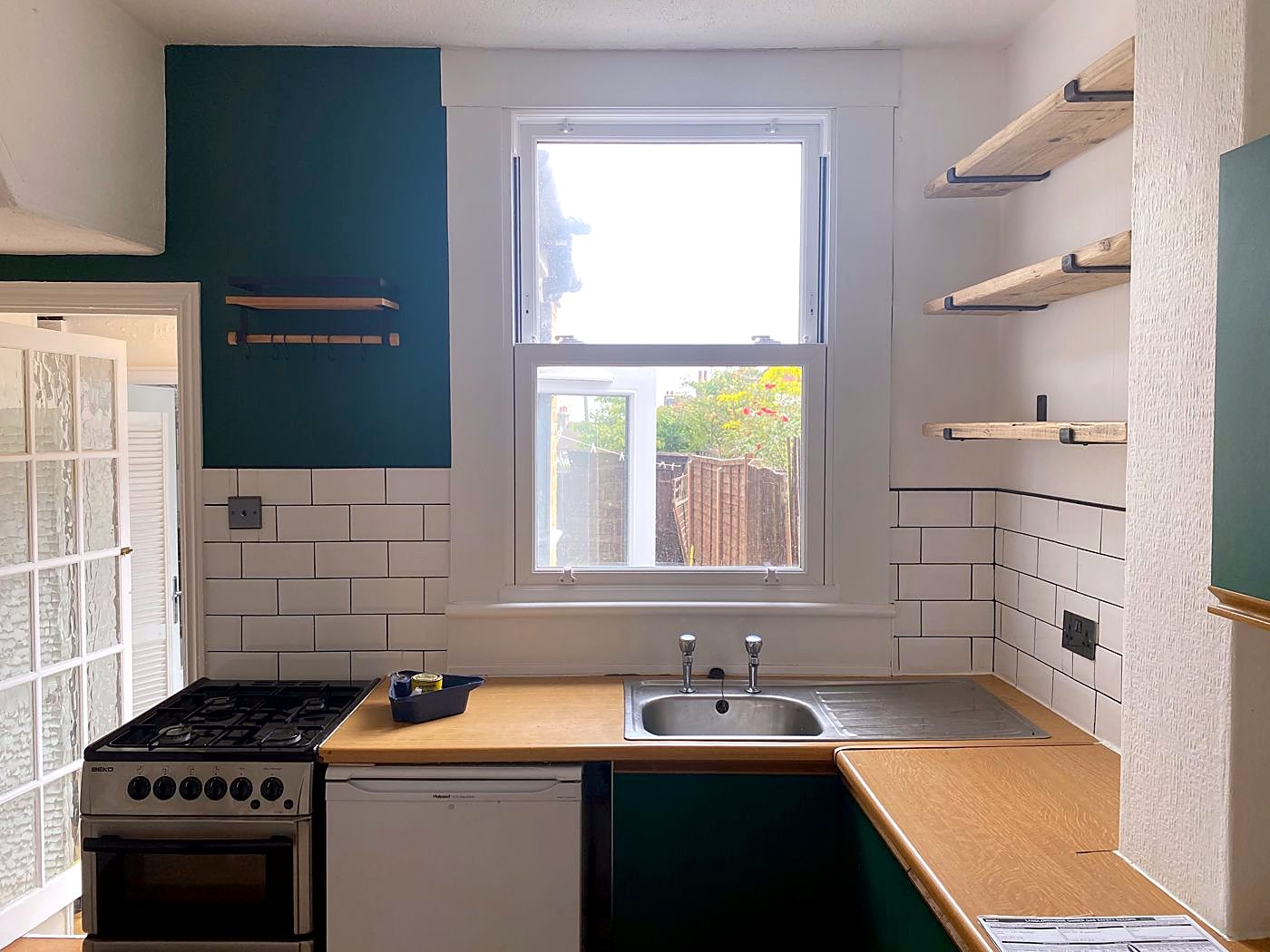 The kitchen before: dated units, a freestanding gas cooker and worn worktops