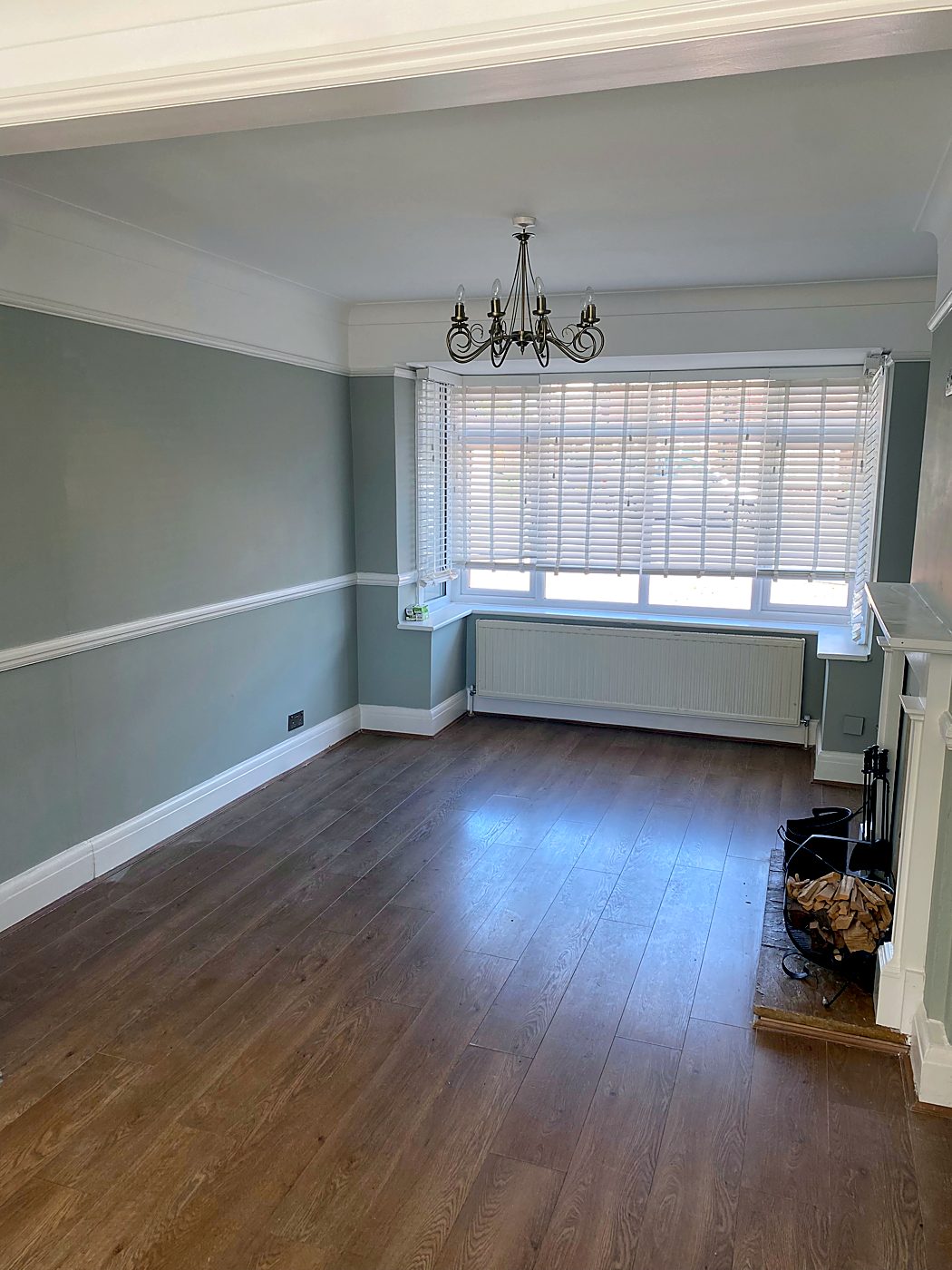 The finished living room with sage green walls, dado rail and chandelier