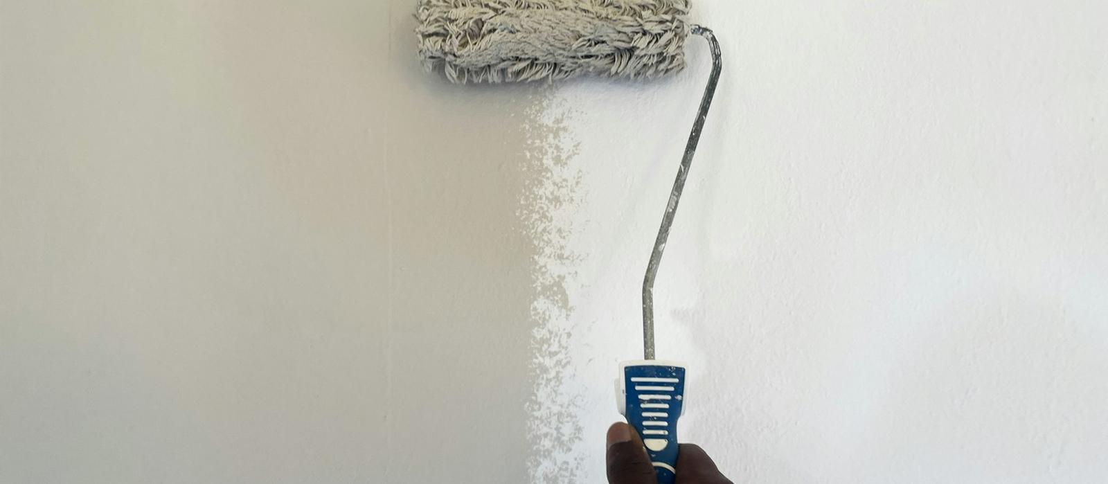 A paint roller on a freshly painted wall